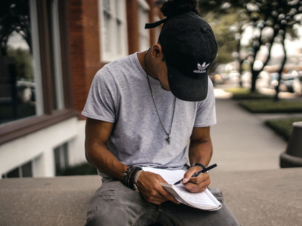 A young man writing on a notebook. 