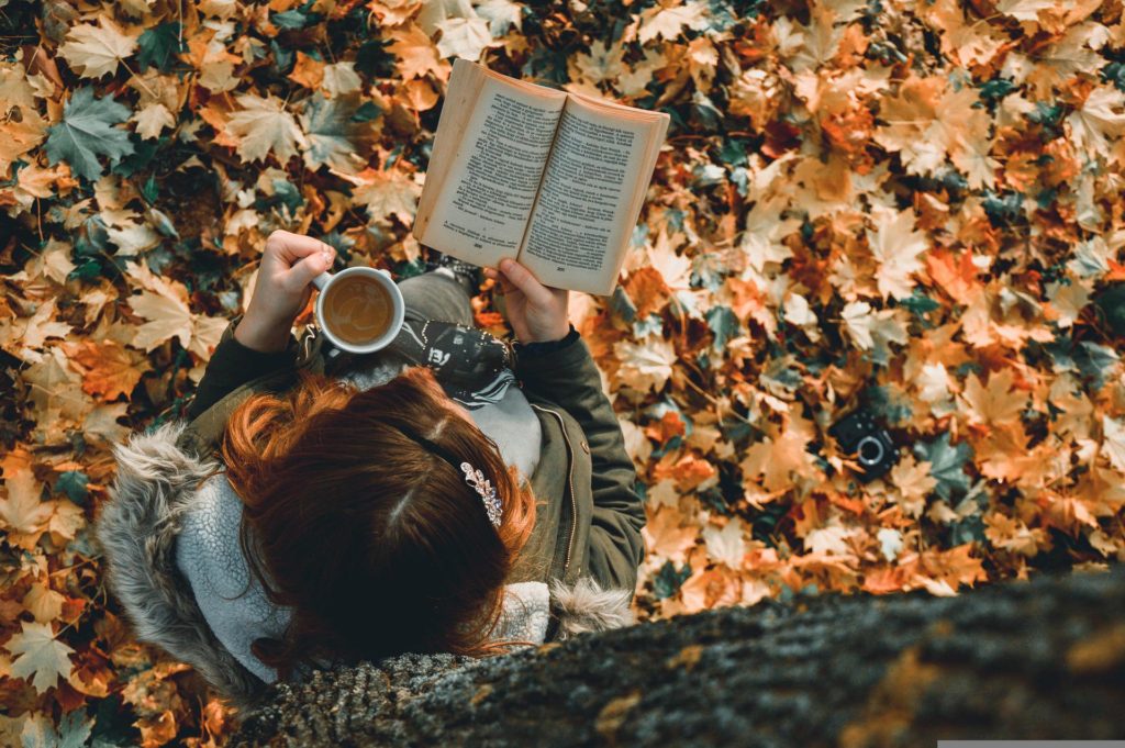 A young woman reading a book as their choice of medium to consume. 