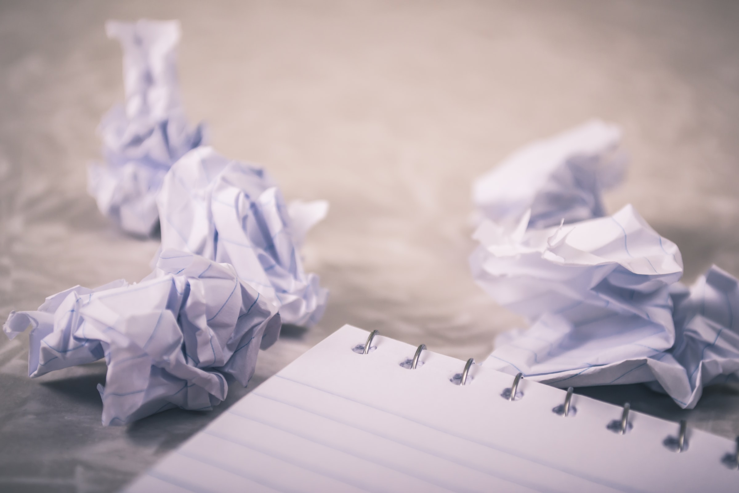 A few crumpled paper balls next to a notebook.