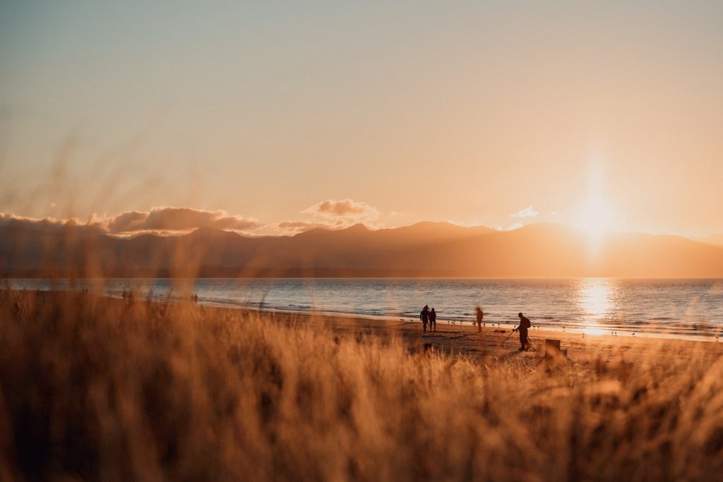 A few people walking on a beach. 