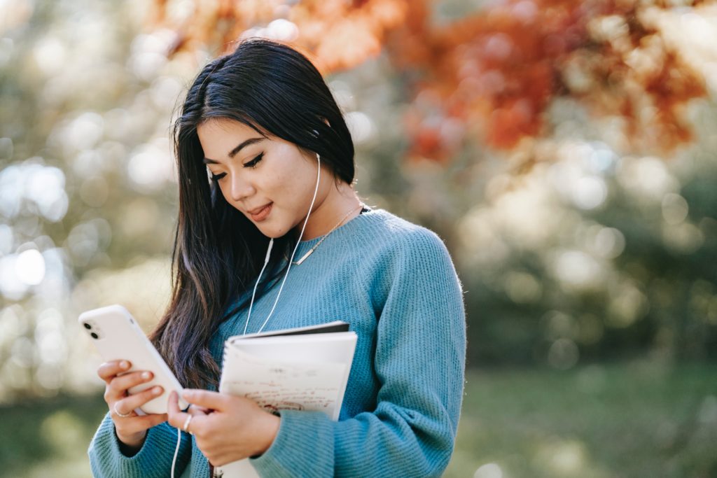 A young woman listening to music on her phone to find inspiration. 