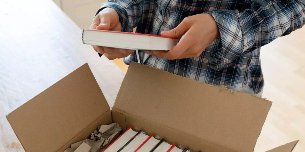 A person pulling out a copy of a book from a box. 