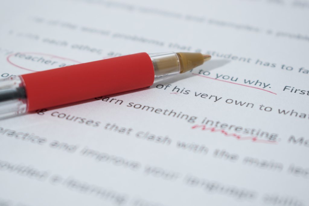 A red pen placed on top of text marked with red ink. 