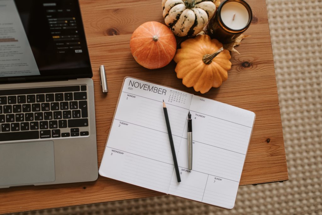 A laptop and planner on a desk. 