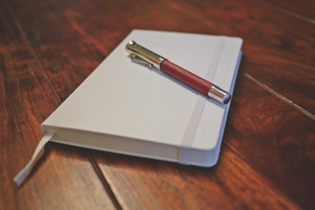 A pen and journal on top of a table. 