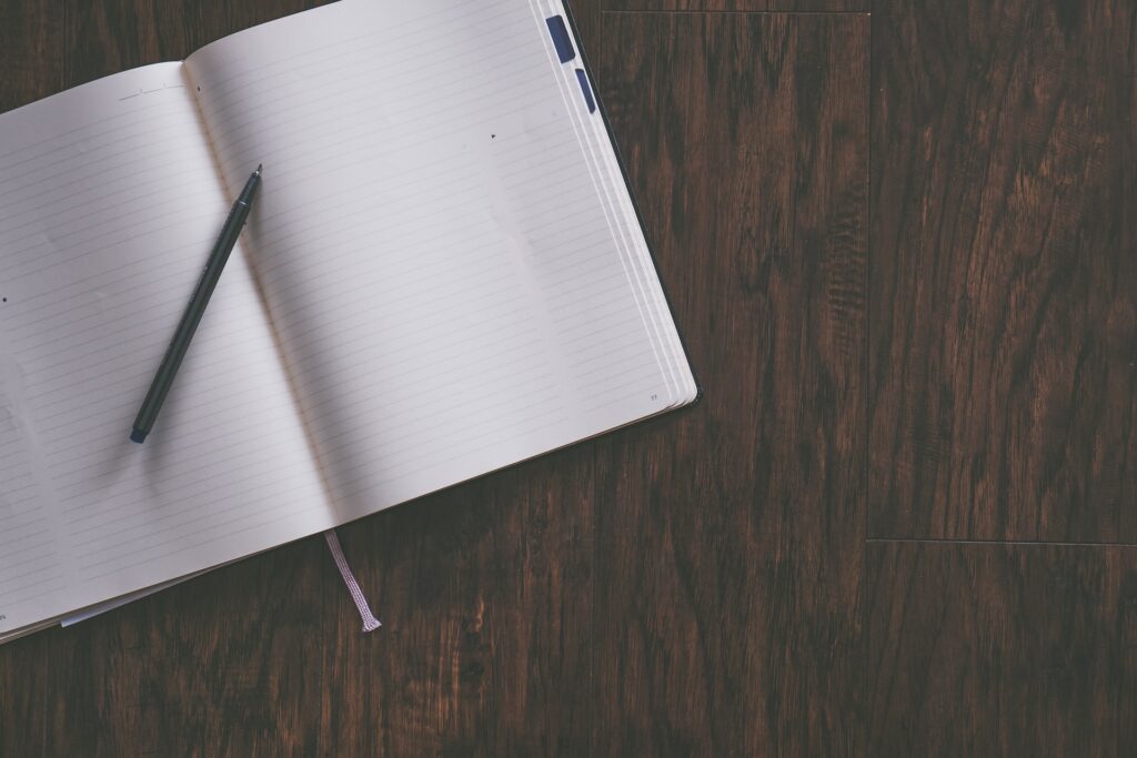 A blank notebook with a pen on top. Harness Your Enthusiasm By Finding What You Love About Writing.  