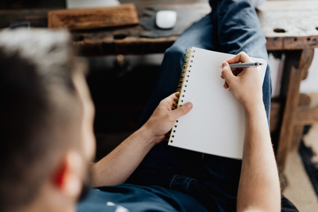 A man rewriting on a blank piece of notebook paper. Rewriting is part of learning to embrace revisions in your own writing. 
