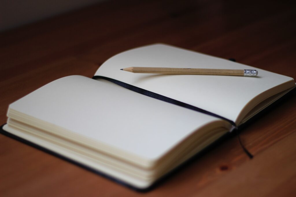 An open blank notebook with a pencil on top. 