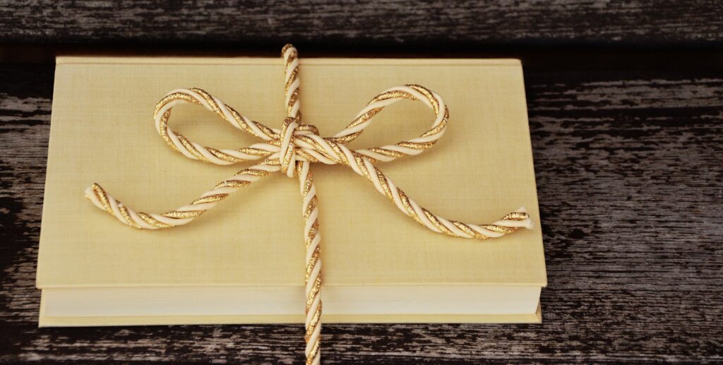 A closed book tied with a rope in the shape of a bow. 