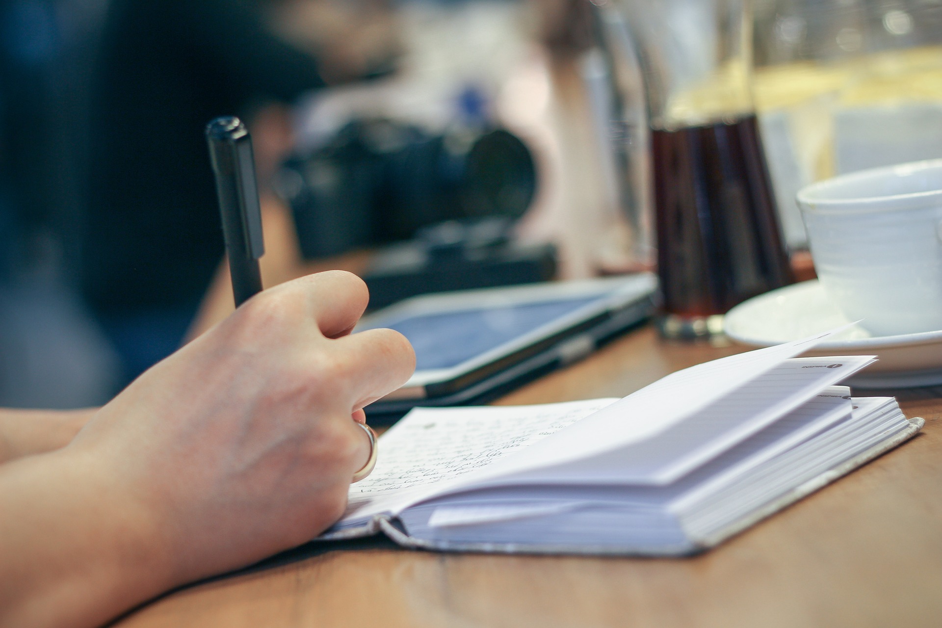 A person writing on a notebook while avoiding the pitfalls of writing a young adult novel.