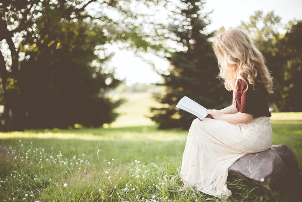 A young girl reading a book outside. 