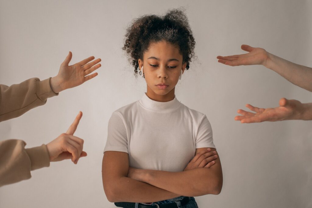 Faceless people scolding discontent girl.
