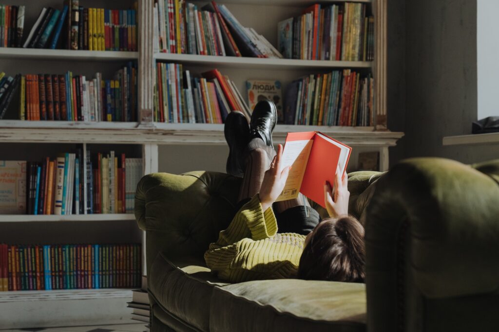 A girl reading a book on a couch. 