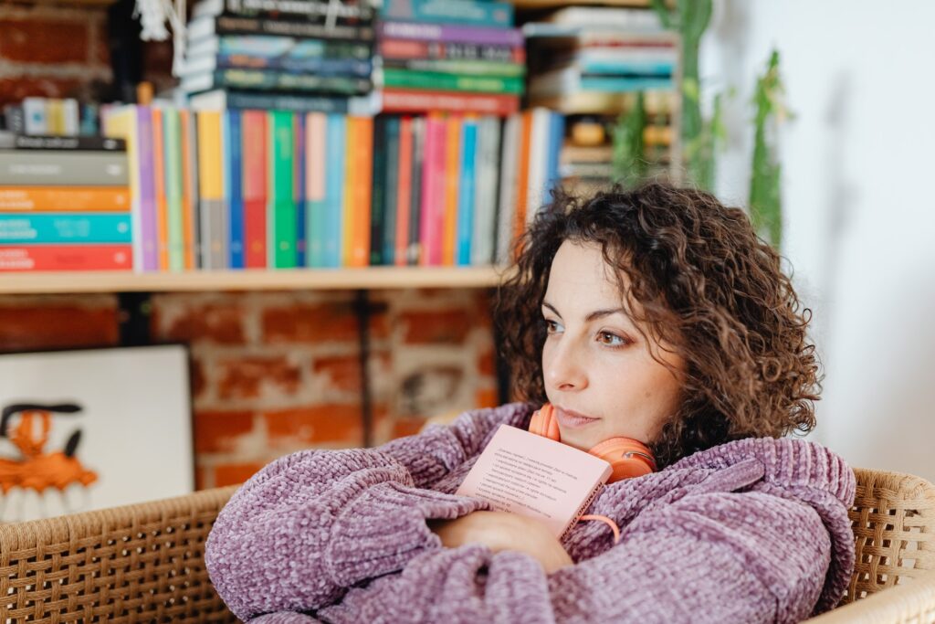 A woman thinking while holding onto a book. Familiar tales is what makes YA fiction messaging speak to all ages.