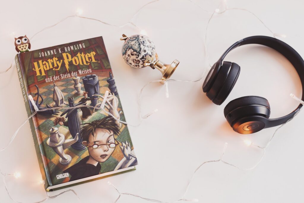 A Harry Potter book and black headphones with a trinket. 