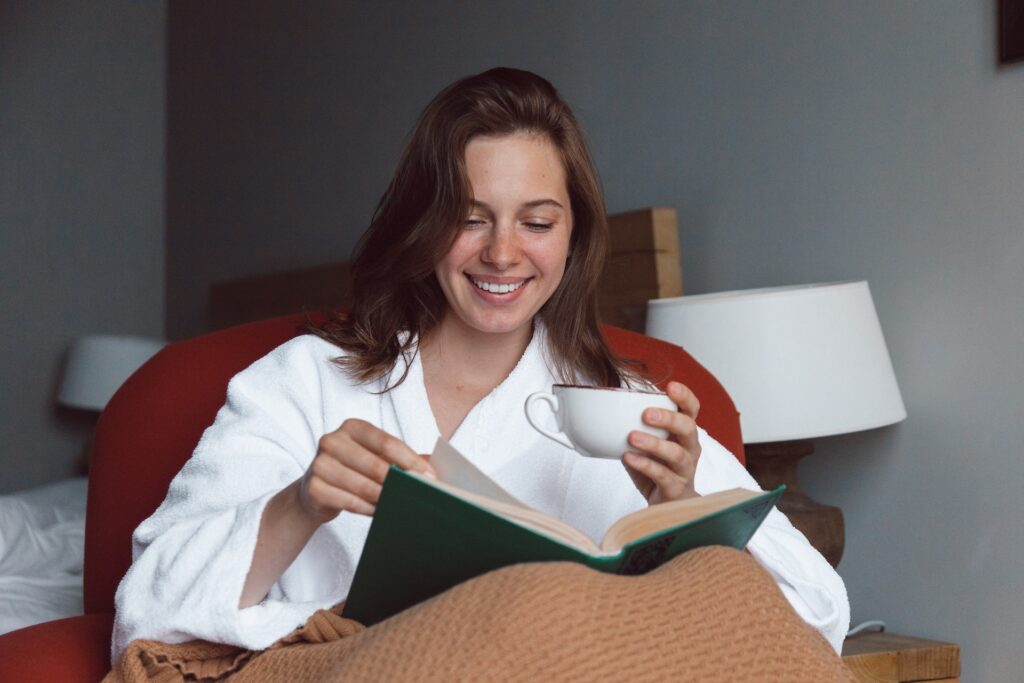 A smiling woman reading book. One of the reason YA fiction messaging speaks to all ages is because YA literature is so well-written. 
