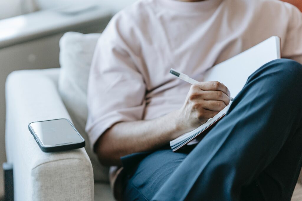 A man writing a novel in a notebook choosing the right tense for his novel