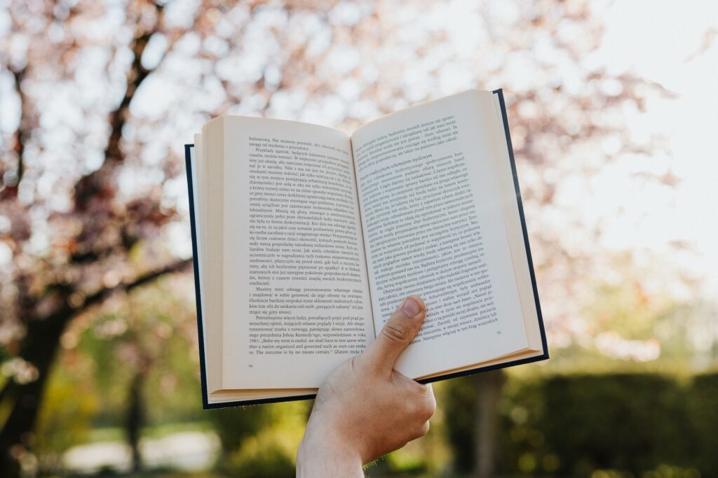 A person holding an opened book, revealing the story's tense. 