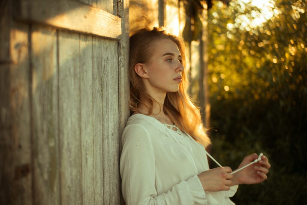 A woman contemplating while leaning on wooden wall. Acceptance is an important change you can write for your YA hero's growth.