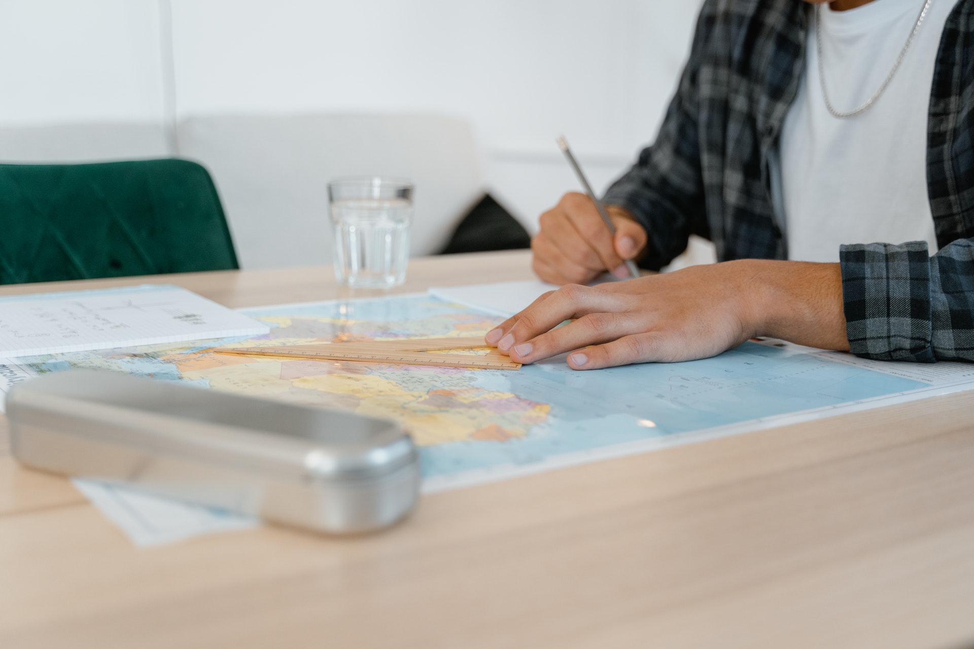 A writer taking notes while looking at a world map.