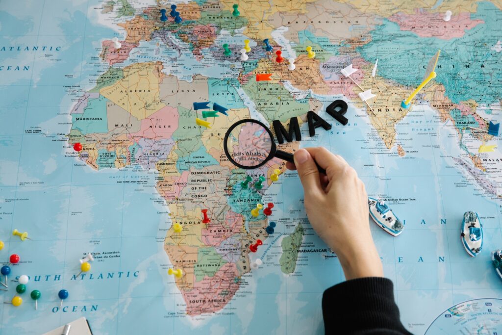 A person holding a magnifying glass over a map.
