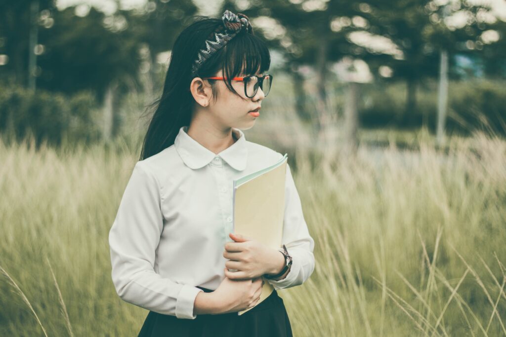 A girl dressed in professional attire holding a brown folder.