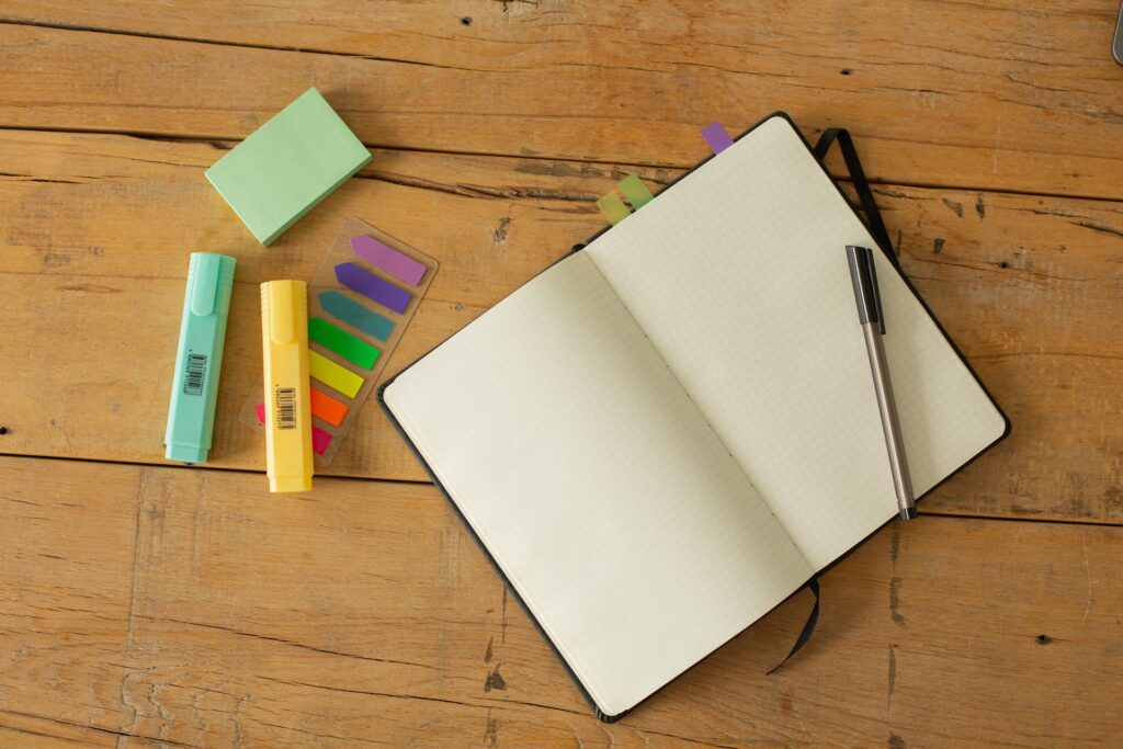 An opened notebook with a pen and highlighters on a table. Strategies to Overcome Writer's Block and Fuel Your Creativity