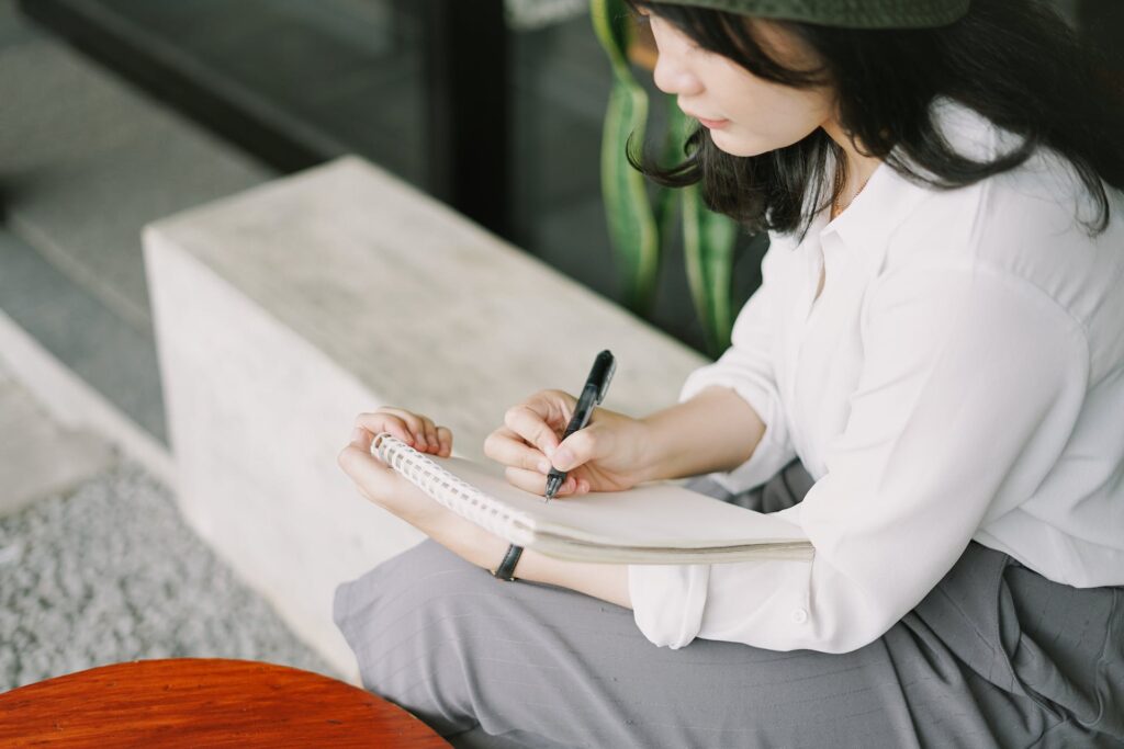 A woman writing on a notebook.