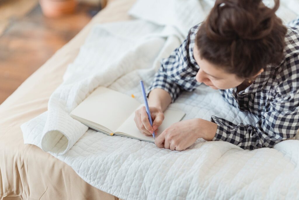 A woman writing in bed.