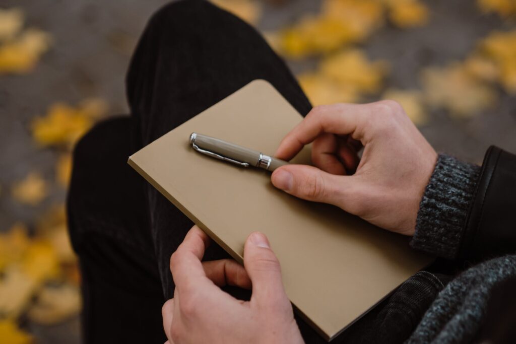 A person holding a pen and notebook.
